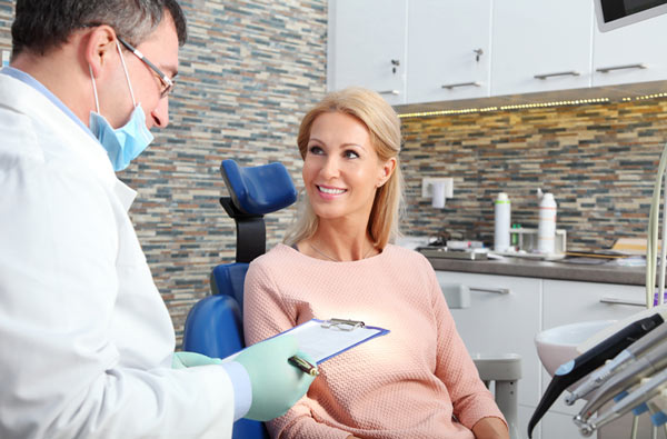 Woman talking to dentist during dental exam from Lakewood Dental Arts in Lakewood, CA