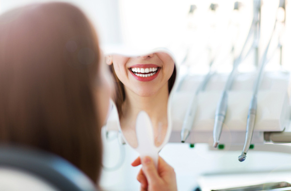 Woman looking at her smile in a mirror in Lakewood, CA