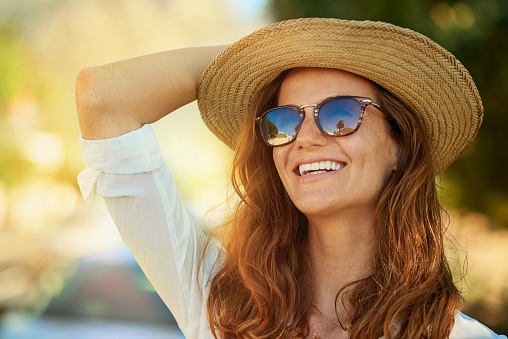 Image of woman with long red hair wearing sun glasses and a sun hat near Lakewood Dental Arts.